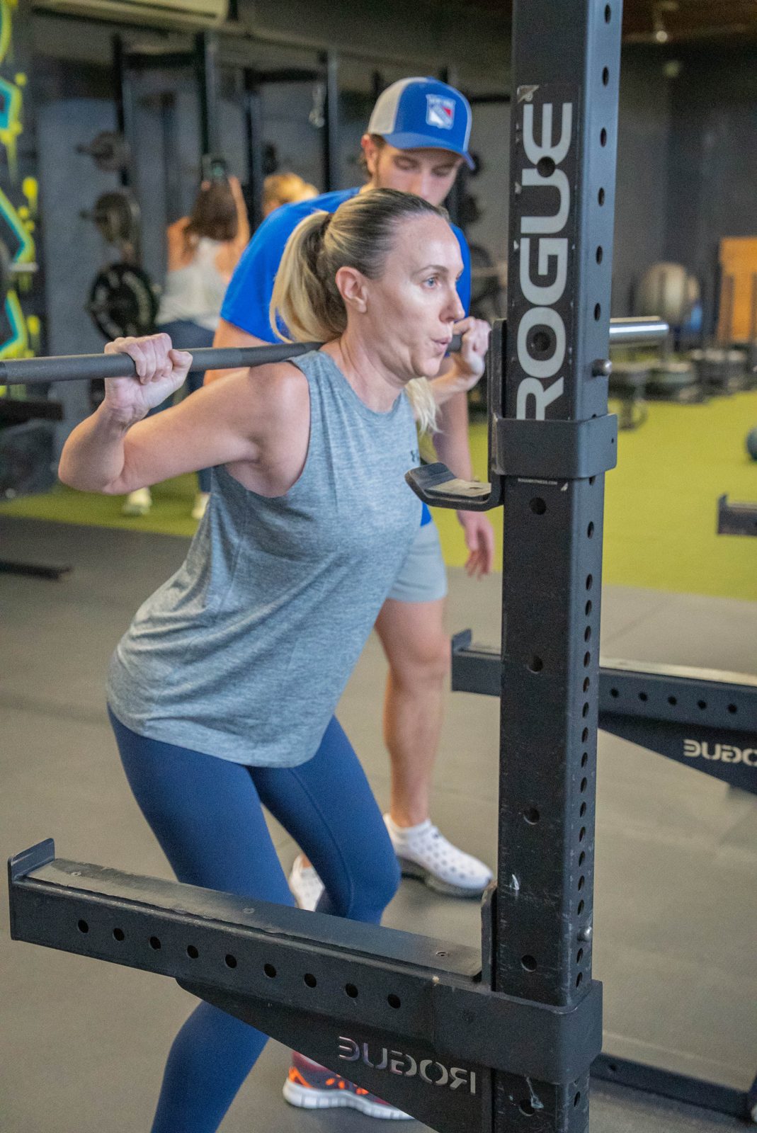RAF coach cueing an adult member's barbell squat at RAF Strength & Fitness in West Hempstead, NY