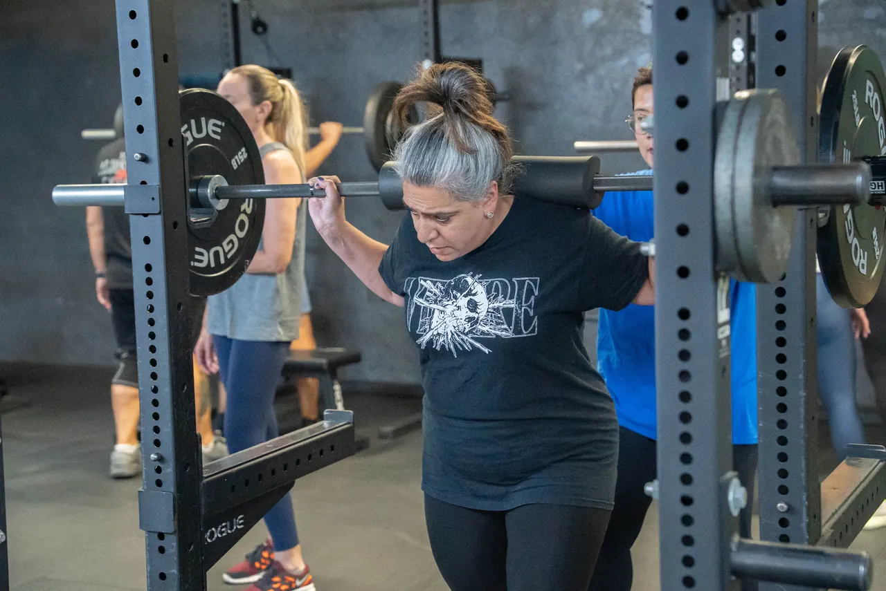 Woman over 40 doing a coached barbell squat at RAF Strength & Fitness in West Hempstead